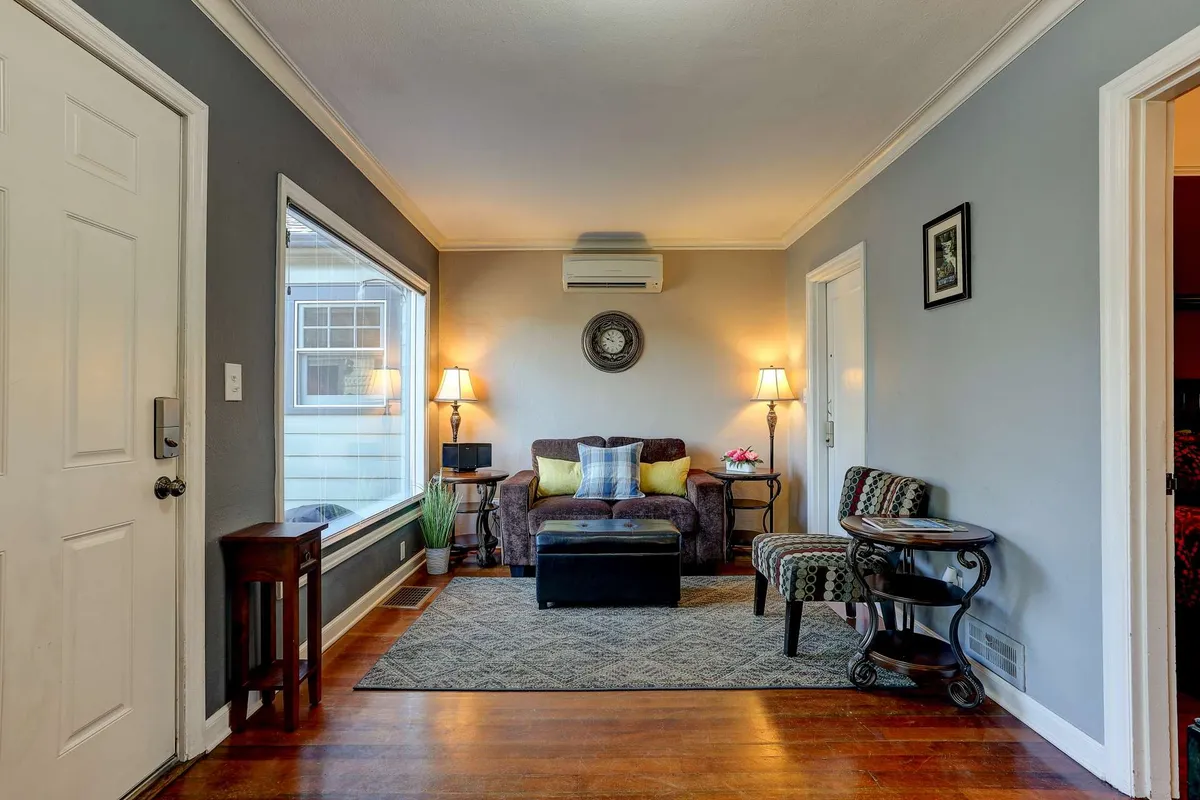 A bright, inviting living room featuring a sofa, cozy rug, lamps, and a large window letting in natural light. The space feels welcoming, perfect for relaxing or socializing after a day of outdoor adventure.