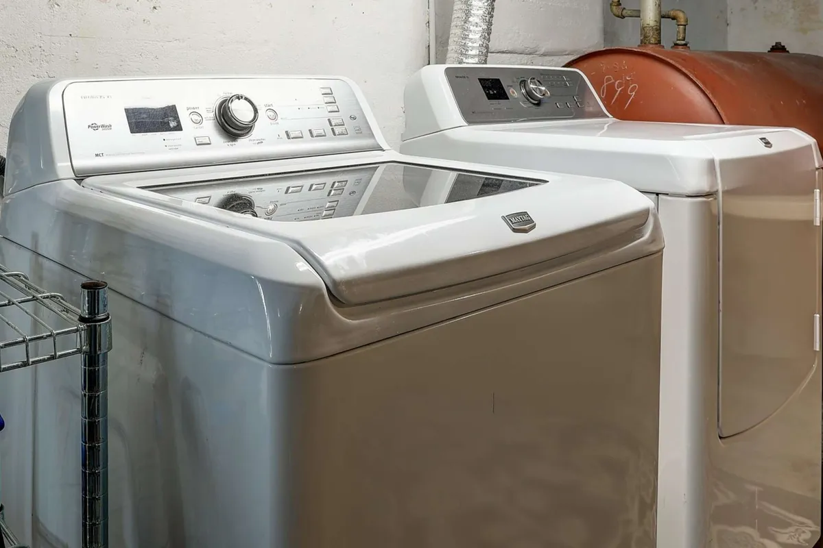 A practical laundry area featuring a washing machine, dryer, and a utility shelf for organizing household items. The space is functional and conveniently accessible for everyday needs.