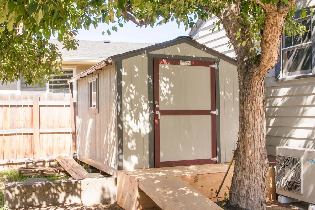 An inviting outdoor area with a shed, a tree, and a pathway, suggesting a tranquil, private space for relaxation or hosting small gatherings. The setting is peaceful, surrounded by nature.
